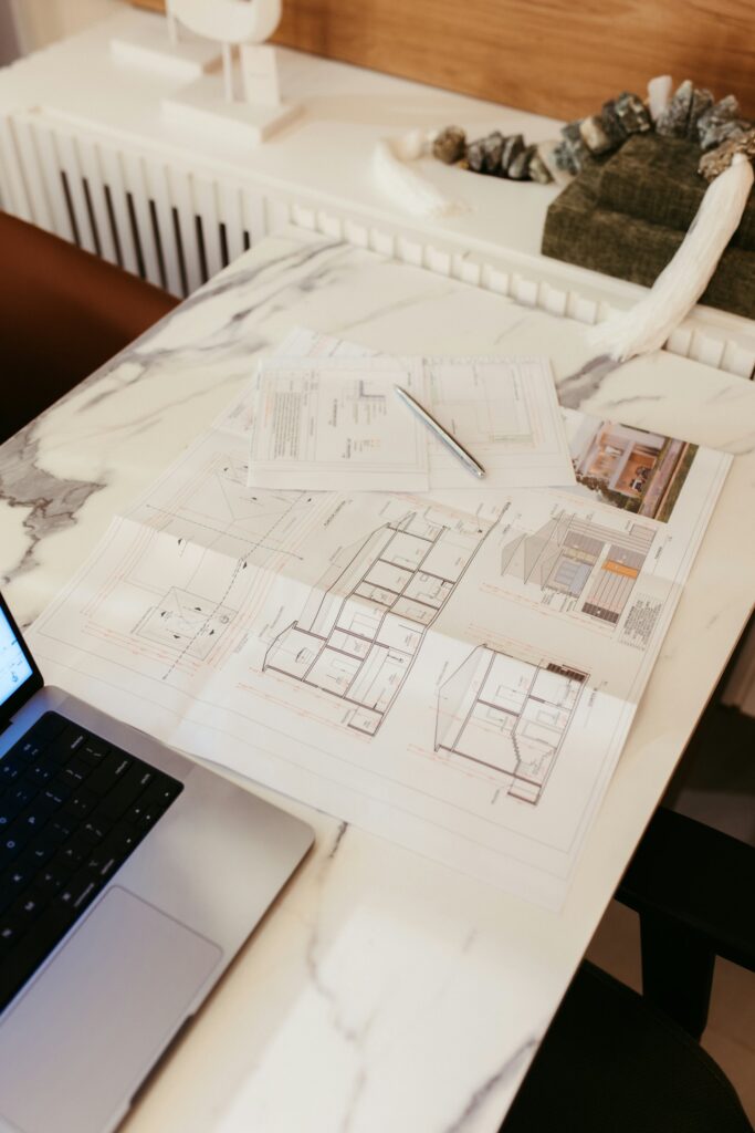 Planos técnicos y portátil sobre una mesa de trabajo